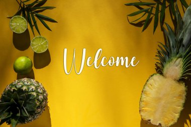 İngilizce Mesajlı Sarı Düz Yatak Hoşgeldiniz. Limon, ananas ve hurma yaprağı gibi tropikal meyvelerle dolu sarı yaz arkaplanı.