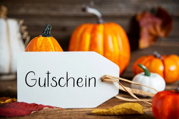 オレンジ色のカボチャと秋の装飾 ドイツ語のテキストGutscheinとラベルで素朴な秋の装飾 英語でバウチャーを意味します — ストック写真
