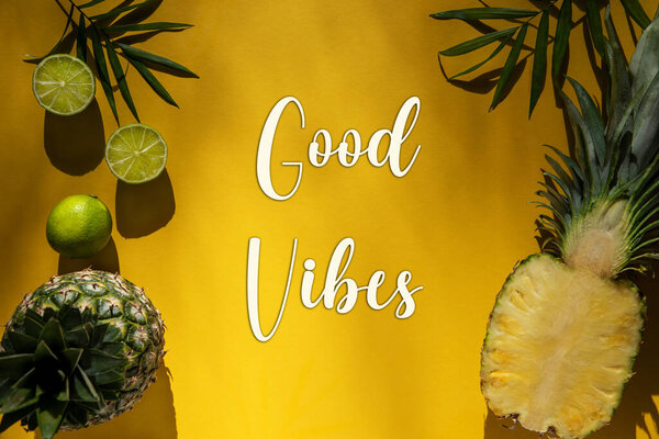 Yellow Flat Lay With English Text Good Vibes. Yellow Summer Background With Tropical Fruits Like Lemon And Pineapple And Palm Leaf.
