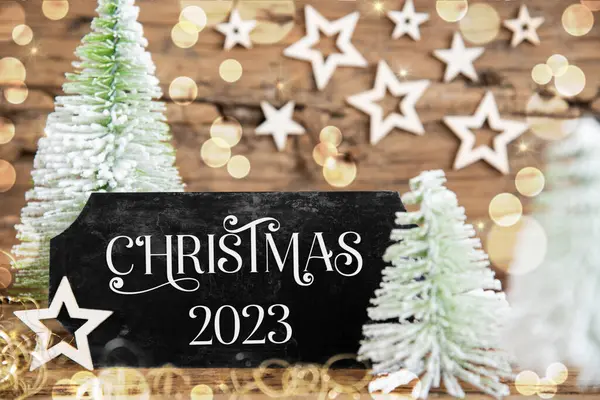 木製のロスティックな背景とテキストクリスマス2023の黒いサインと緑の白いクリスマスツリー — ストック写真