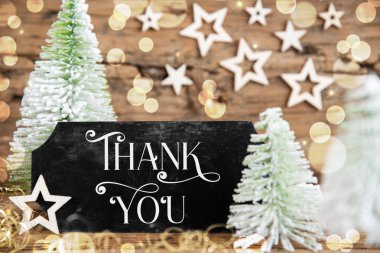 Ahşap arka planı olan yeşil beyaz Noel ağaçları ve mesajlı siyah bir tabela.