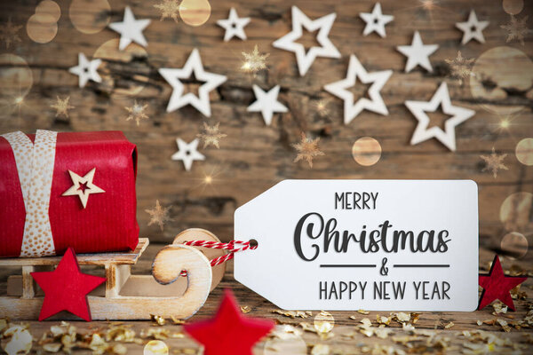 Wooden Sled With Red Gift And Rustic Christmas Bokeh Background With Label With Text Merry Christmas And Happy New Year