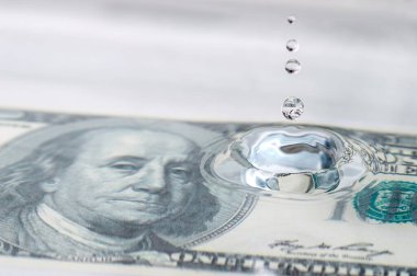 100 dolarlık büyüyen ekonomi konseptiyle su damlaları ve dalgalar.