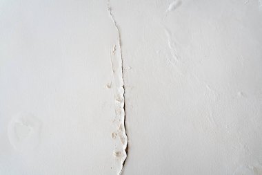 Çatı manzarası ve duvardan içeri süzülen yağmurlu bir çatlak hasar yaratıyor ve boya soyuluyor.