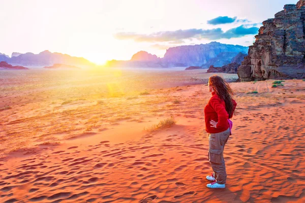 ヨルダンの美しい赤い砂漠の景色を楽しむ砂丘の上に滞在している赤いジャケットの若い女性探検家の後部ビュー — ストック写真