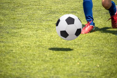 Shot of ball and young boy playing soccer on a sports field