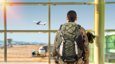 Shot of a soldier in a military uniform looking through the window at an airport