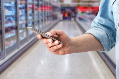 Cropped shot of a man using a mobile phone in a supermarket