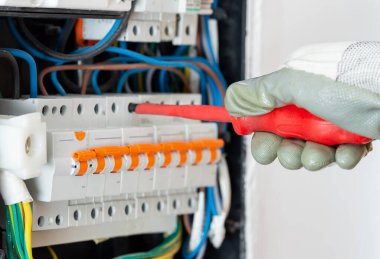 Closeup of electrician engineer works with electric cable wires of fuse switch box. Electrical equipment and automatic.