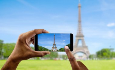 Tourist in Paris visiting landmark Eiffel tower, sightseeing in France, man taking photo on mobile phone