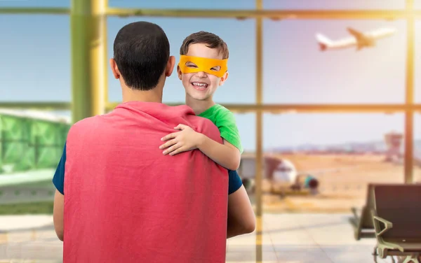 A little boy afraid of flying in a plane who hugs his father with love, wears an orange mask, dresses in superhero costumes who confides in him the pope at the airport