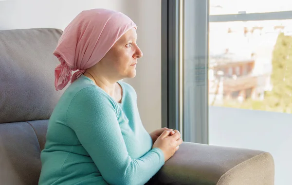 Young woman with cancer in head scarf indoors at home with copy  space.