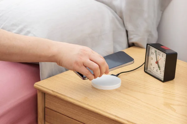 Woman Charging Smartphone Using Wireless Pad Bedroom Home Stockfoto