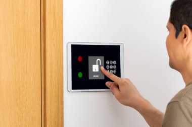 Man entering authorization code pin on home alarm keypad. Home security concept