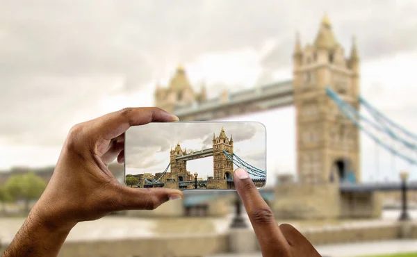 Tourist holding mobile camera and photographing london bridge in england