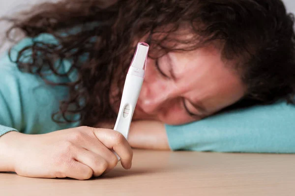 Single sad woman complaining holding a pregnancy test at home