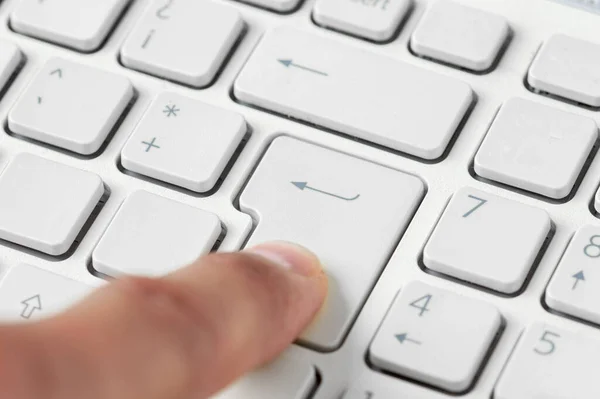 Close up of a finger pressing the enter key