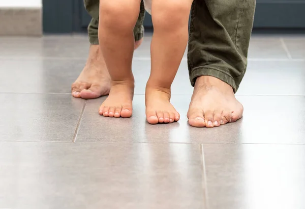Cropped shot of an unrecognizable little boy learning to walk with his father behind his at home