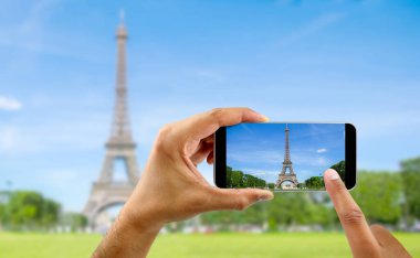 Tourist in Paris visiting landmark Eiffel tower, sightseeing in France, man taking photo on mobile phone