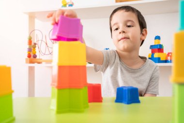 Geleceğimin yapı taşları. İlgili bir anaokulu çocuğu plastik bloklu bir şey inşa ediyor..