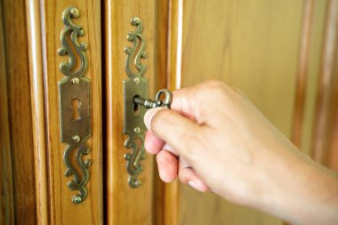 Male hand puts the key in the keyhole of a clothes closet