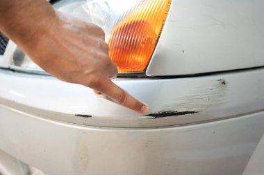 Car service worker examining vehicle body for scratches and damages while taking a car for professional automotive detailing