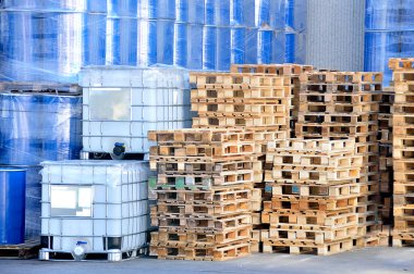 A stack of freight containers in rows at the factory with liquid inside and stacked pallets