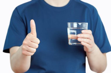 Front view close up of a woman holding a water glass with thumb up isolated on white