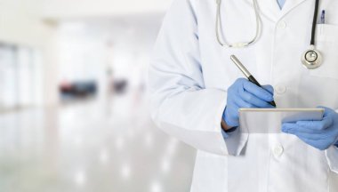 Hastanedeki dokunmatik bilgisayarına yazı yazan genç bir doktorun kırpılmış görüntüsü.