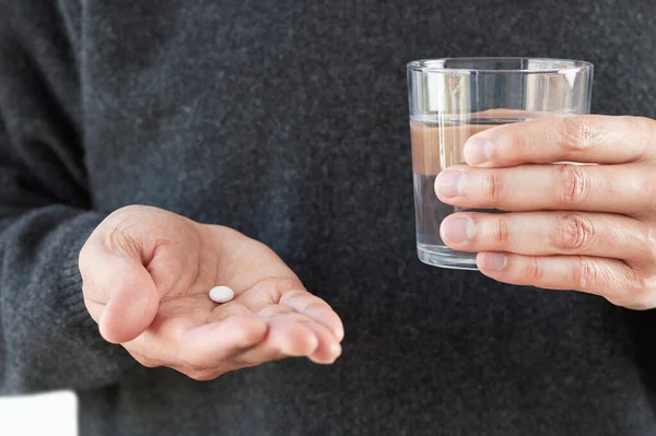 錠剤と水のガラスを示す認識できない若い男の手のショット — ストック写真