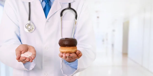 stock image Closeup of a male doctor hand holding sugar and donuts  at hospital