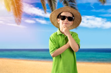 Güneş gözlüğü takan, yeşil tişörtlü, elleri çenesinde tropikal plajlar giyen soru soran, düşünceli bir çocuk. Dalgın bir yüz. Şüpheye kapılma ve yana bakma