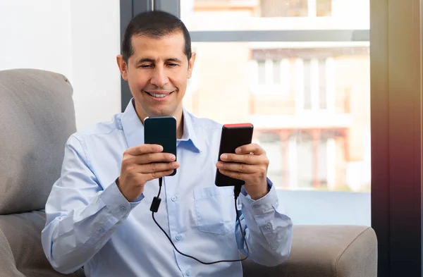 Szczęśliwy Człowiek Ładowania Smartfona Przenośnej Ładowarki Siedzi Kanapie Domu — Zdjęcie stockowe