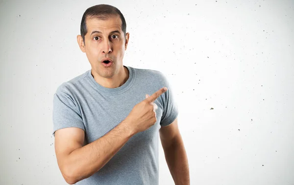 Knappe Man Met Casual Grijs Shirt Betonnen Muurachtergrond Verrast Wijzend — Stockfoto