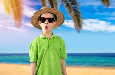 Tropikal plajda yeşil t-shirt şapkalı bir çocuk, korku ve heyecan dolu bir yüz ifadesiyle korkmuş ve şok olmuştu..