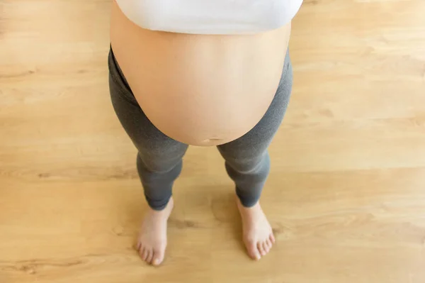 自宅で妊娠中の女性の裸の腹の高い角度のショットをトリミング — ストック写真