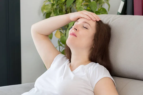 自宅でソファの上で頭痛の種の若い女性のショット — ストック写真