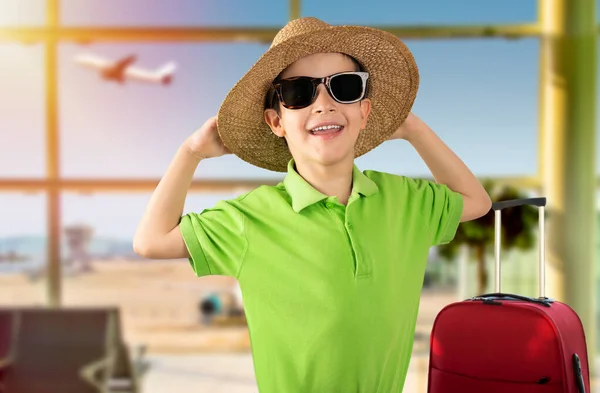 空港の幸せな肖像画笑顔で緑のTシャツの帽子のサングラスを着て休暇中の子供やカメラを見て 正の人 — ストック写真