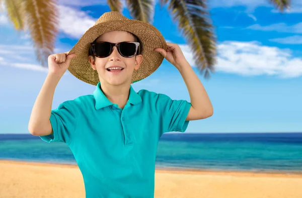Chłopiec Wakacjach Niebieskiej Koszulce Okulary Przeciwsłoneczne Kapelusz Plaży Szczęśliwy Uśmiech — Zdjęcie stockowe