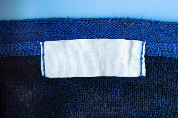 Weiße Leere Wäschepflegeetikett Auf Blauem Polyester Sporthemd Hintergrund — Stockfoto