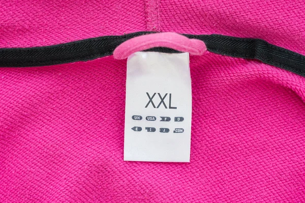 Xxlサイズの服ラベルタグ 白い生地 ピンクで隔離された 詳細なマクロクローズアップ — ストック写真
