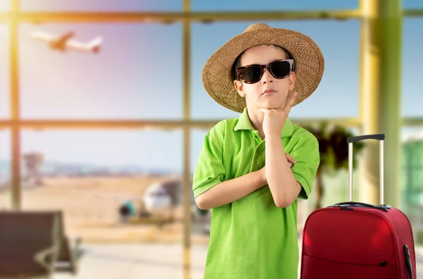 休暇中の男の子の質問について考えてあごの手で空港で緑のTシャツの帽子をかぶってサングラスをかけて 包括的な表現 ペナルティ フェイス 疑いの概念と脇を見る — ストック写真