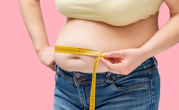 ピンクの背景に測定テープで彼女の腰を測定肥満女性の股間 — ストック写真