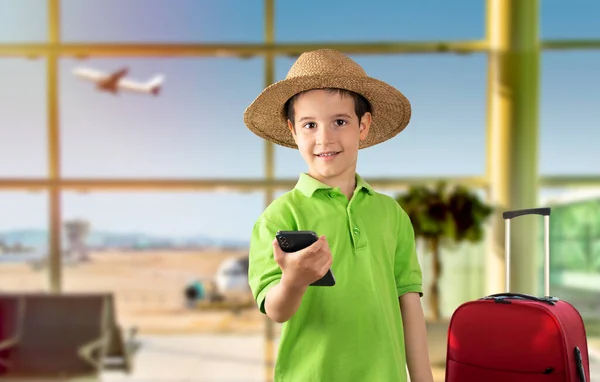 小男孩用智能手机看着镜头 满脸喜色 头戴礼帽 自信地微笑着 在机场上露出牙齿 — 图库照片