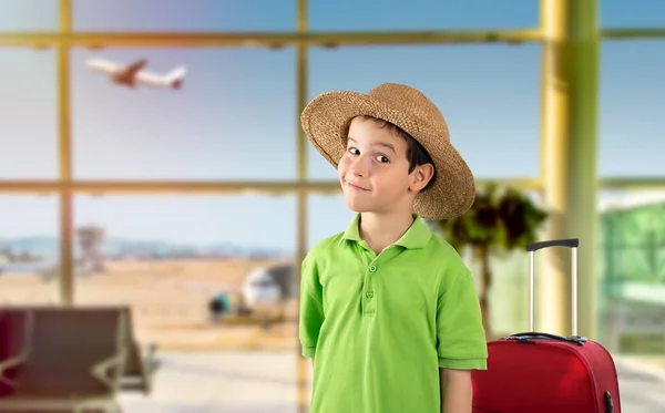 休暇中に緑のTシャツの帽子をかぶって子供空港の幸せな顔はカメラを見て笑っている 正の人 — ストック写真