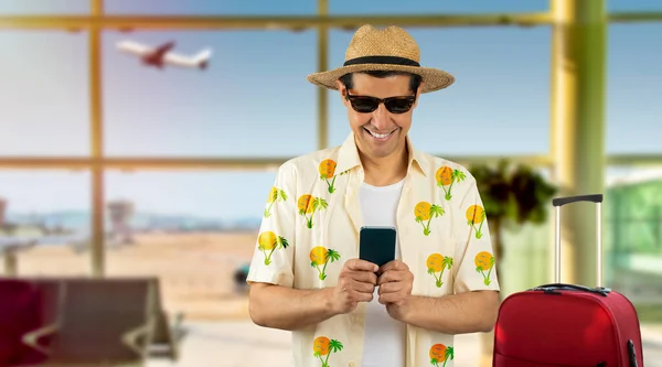 在机场用智能手机发短信的拉丁男人 脸上挂着快乐的表情 脸上挂着自信的微笑 露出牙齿 — 图库照片