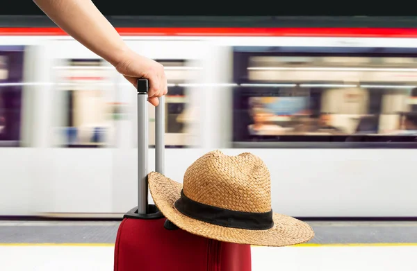 赤いスーツケースを着た電車の駅で待っているカジュアルな旅行者の手 — ストック写真