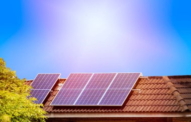 Güneş panelleri güneşin altında evin kiremitli çatısında. Kendi ihtiyaçları ve satışı için fotokopi alanı ile elektrik üretimi.