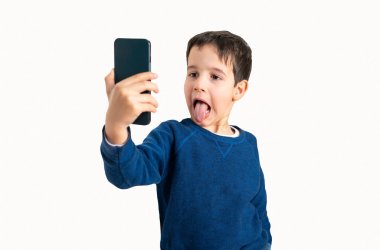 Aptal tarafını gösteriyor. Beyaz arkaplanlı bir selfie çekerken dilini dışarı çıkaran bir çocuk resmi.
