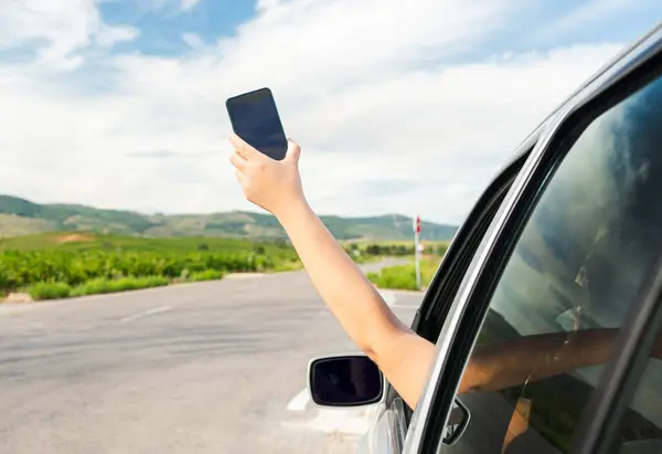 Hand with a phone searching for signal from a car on a highway